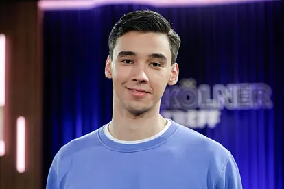 Diego Pooth lächelt in einem blauen Pullover in die Kamera.