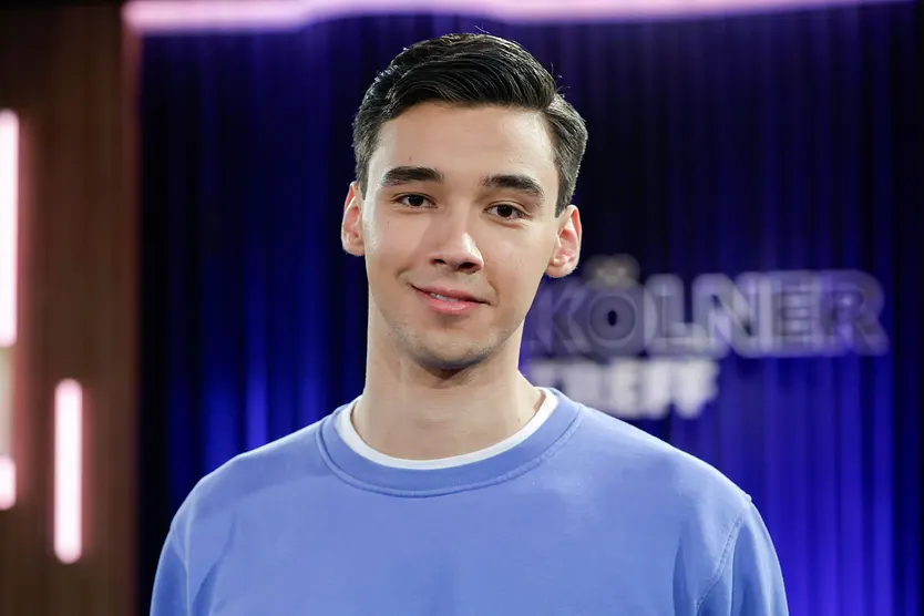 Diego Pooth lächelt in einem blauen Pullover in die Kamera.