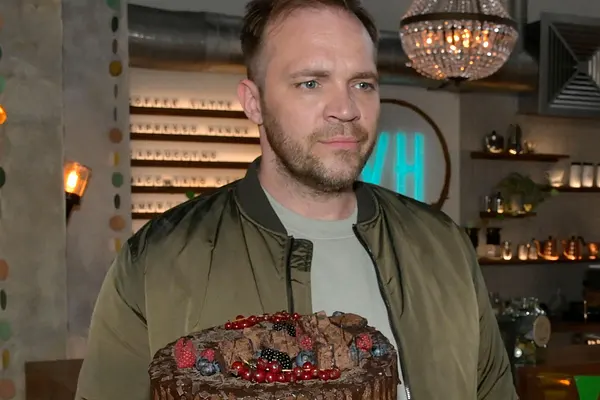 Erik mit Kuchen in der Hand, neben ihm steht Nina und schaut ihn kritisch an.