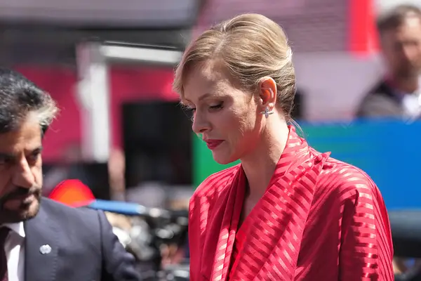 Fürstin Charlene trägt ein rotes Kleid und schaut nach unten. 