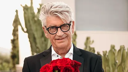 Franz Stärk im schicken schwarzen Anzug und einem Strauß rote Rosen
