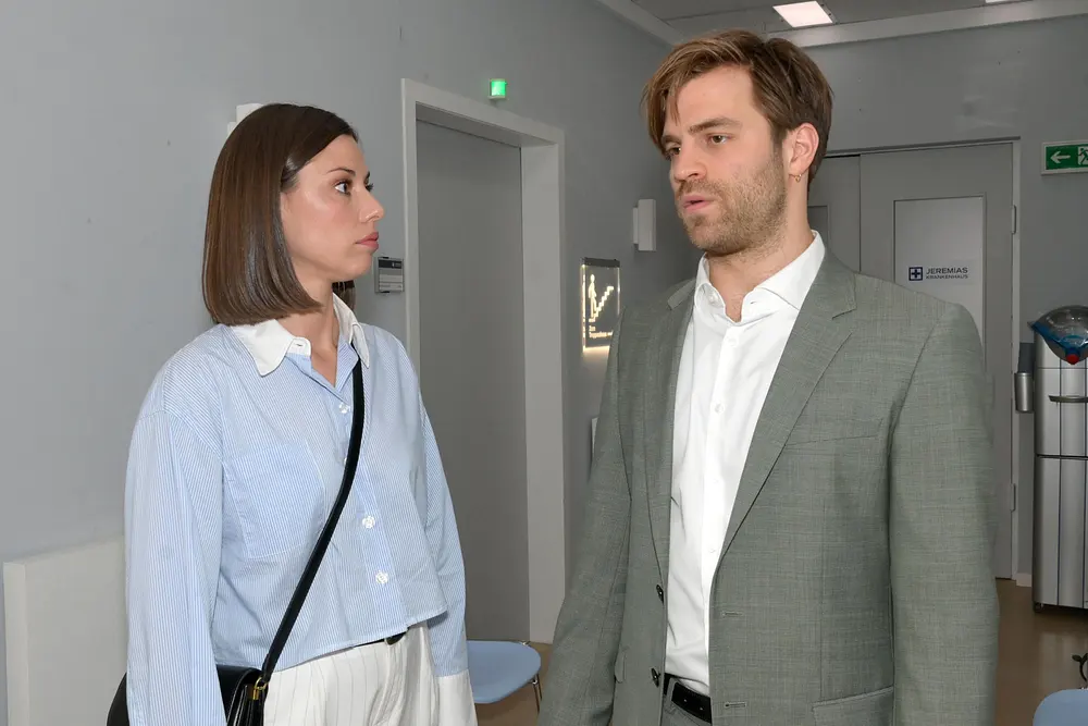 GZSZ-Szene: Julian und Matilda stehen sich im Krankenhausflur gegenüber. Sie schaut ihn kalt an, er blickt niedergeschlagen in die Ferne.