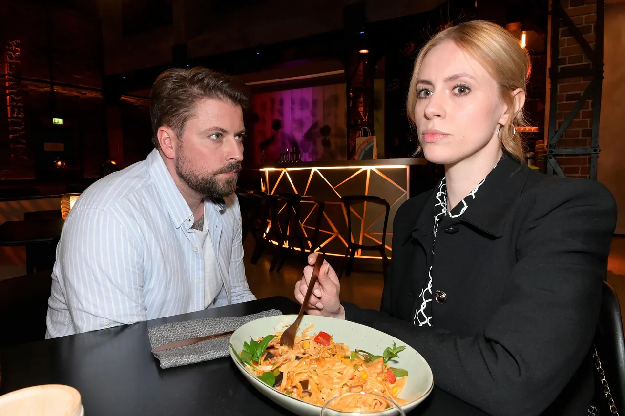 gzsz-zoe-kommt-gerner-auf-die-schliche GZSZ-Szene: Zoe sitzt vor einem Teller Pasta, John sitzt neben ihr und schaut sie eindringlich an. - Foto: GZSZ/Rolf Baumgartner