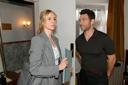 Zoe mit ernstem Blick, während Carlos sie verschmitzt anlächelt.