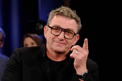 Hans Sigl schaut in die Kamera und zeigt mit einem Finger in die Ferne.
