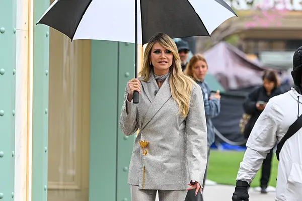 Heidi Klum mit einem Regenschirm in der Hand schaut zur Seite.