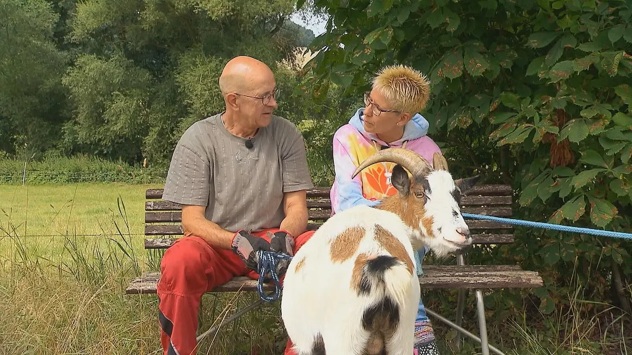 "Bauer sucht Frau"-Kandidat Herbert sitzt mit Carola auf einer Bank, vor ihnen steht eine Ziege.