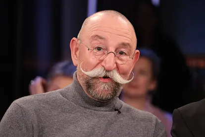 Horst Lichter trägt einen grauen Rollkragenpullover. Für den Sommer hat er sich aber ein freizügigeres Outfit ausgesucht.