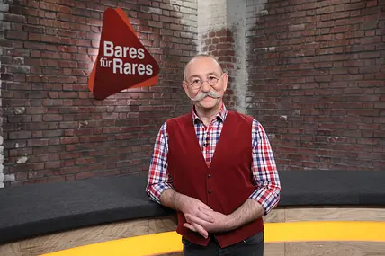 Horst Lichter lehnt sich an den Händlertisch im "Bares für Rares"-Studio.