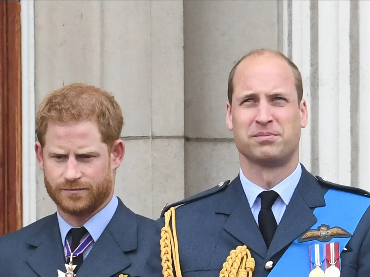 imago127659783 Prinz Harry und sein Bruder William stehen nebeneinander auf einem Balkon. Sie haben beide einen ernsten Gesichtsausdruck und schauen sich nicht an. - Foto: IMAGO / Parsons Media