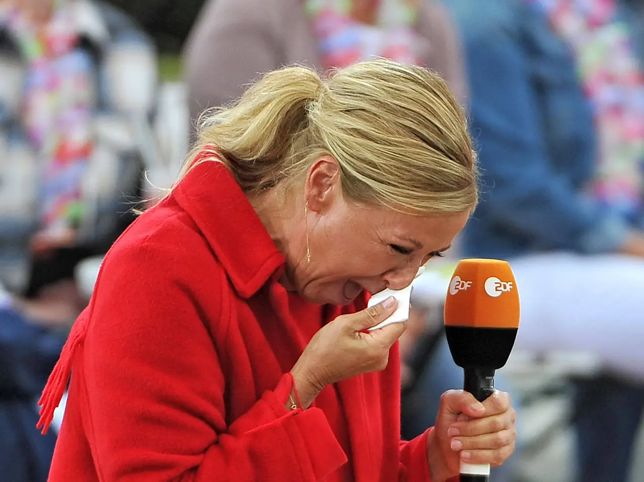 Andrea Kiewel, ganz in Rot gekleidet, weint auf der Bühne des ZDF-Fernsehgarten und drückt sich ein Taschentuch ins Gesicht.  - Foto:  IMAGO / STAR-MEDIA