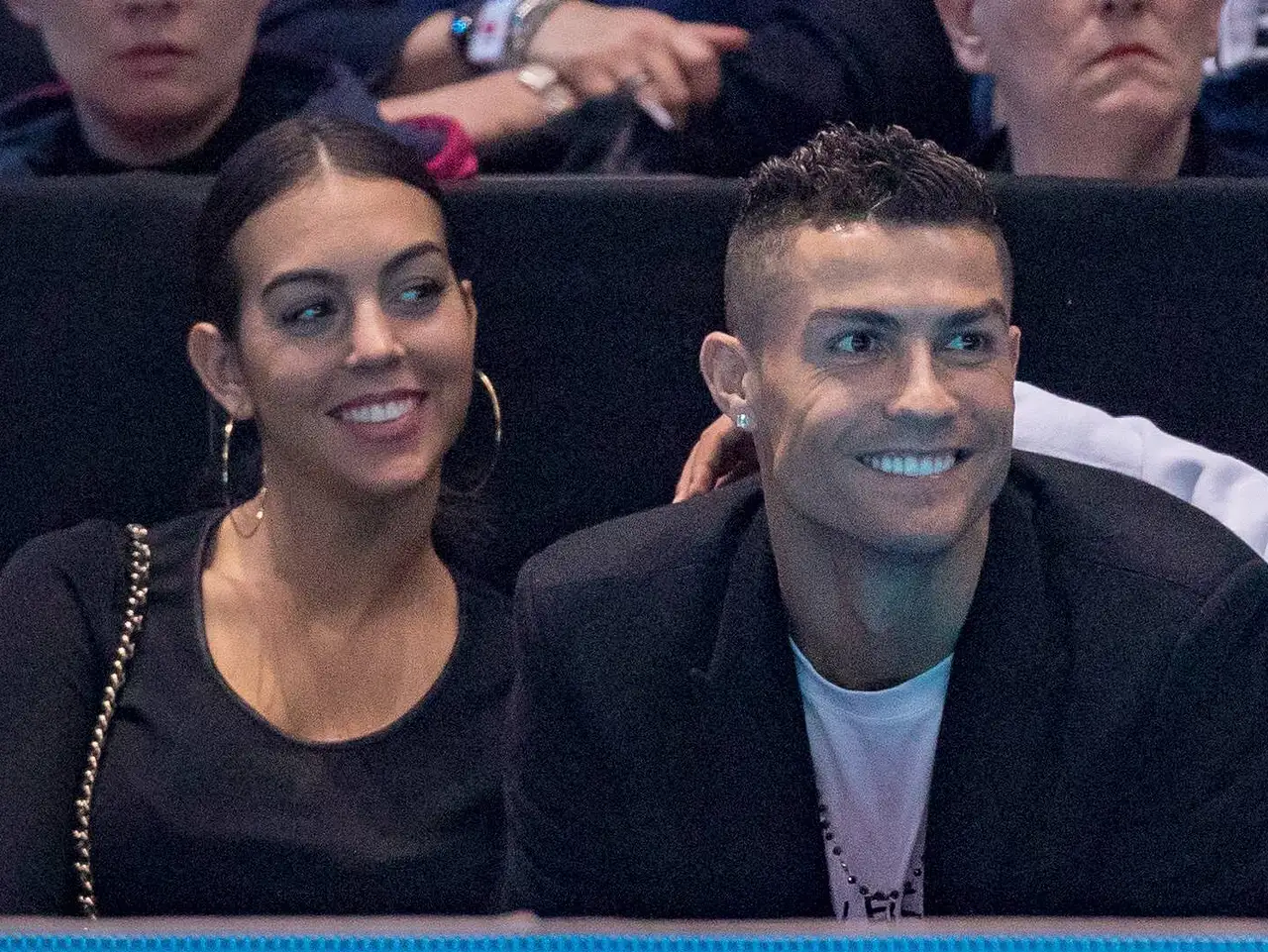 imago37482294 Cristiano Ronaldo und seine Verlobte sitzen nebeneinander. Sie schaut hinter ihm zu seinem Sohn Cristiano Jr. und Ronaldo schaut lächelnd nach vorne. - Foto: IMAGO / PRiME Media Images