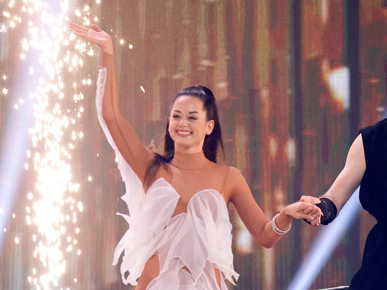 Malika Dzumaev, hier 2024 bei einem Lets Dance-Auftritt in weißem Kleid und neben einer Lichterfontäne, meldet sich zurück.  - Foto:  IMAGO / Panama Pictures