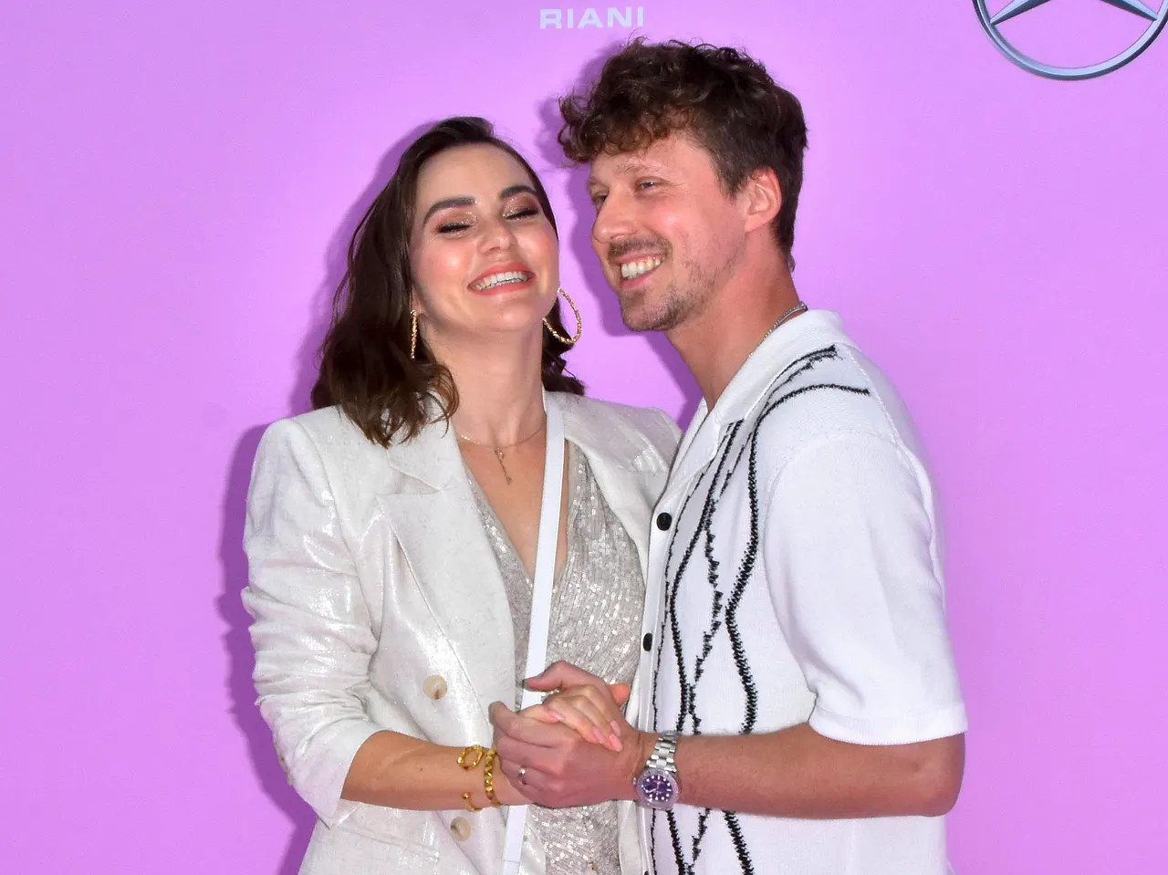 imago803959471 Renata Lusin und Valentin Lusin turteln in weißen Outfits vor pinkem Hintergrund. Liebevoll halten sich die Eltern der kleinen Stella an den Händen. - Foto: IMAGO / BREUEL-BILD