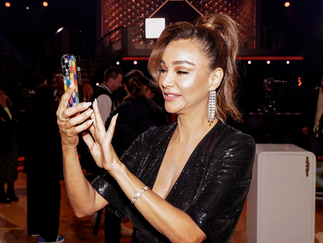 imago806813314 Verona Pooth, in einem Glitzerkleid und mit hochgebundenen Haaren, tippt etwas auf ihrem Handy ein. - Foto: IMAGO / Future Image