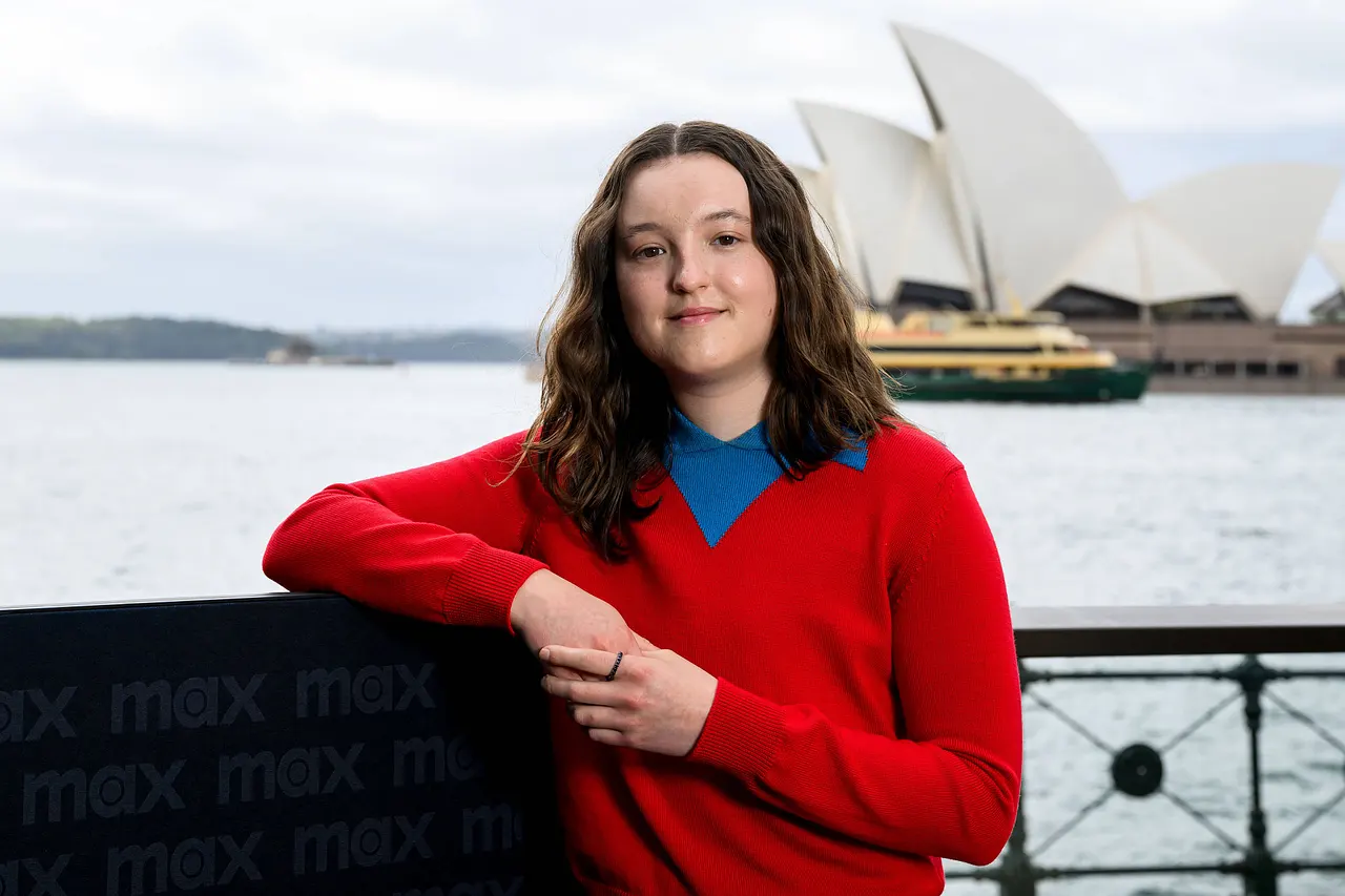 Bella Ramsey verliebt Last of Us-Darstellerin Bella Ramsey posiert allein in rotem Oberteil vor Meeres-Hintergrund. - Foto: IMAGO / AAP