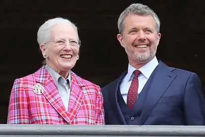 Margrethe II. und ihr Sohn Frederik X. stehen nebeneinander und mit einem strahlenden Lächeln im Gesicht auf einem Balkon.