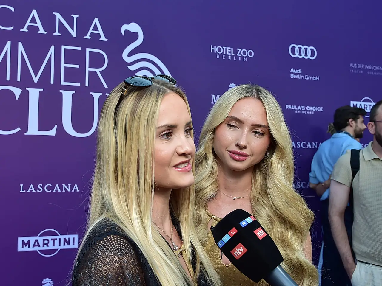 imago823903966 Shania und Davina Geiss stehen vor einer Fotowand des Lascana Summer Club-Events. Ihnen wird ein Mikrofon entgegengehalten. Im Hintergrund sieht man zwei Männer. - Foto: IMAGO / Photopress Müller