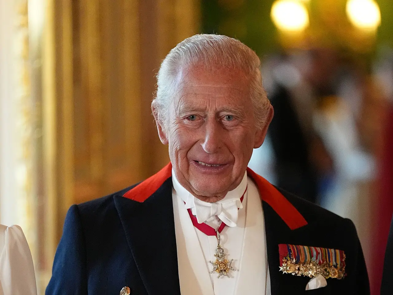 imago824749611 König Charles III. in einem Jackett voller Orden. Er lächelt und es ist leicht erkennbar, dass sein linkes Auge Blut unterlaufen ist. - Foto: IMAGO / i Images