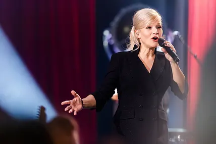 Ina Müller singt auf der Bühne in ein Mikrofon