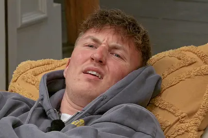 Jonny Jaspers schaut irritiert, während er auf dem Sofa liegt.