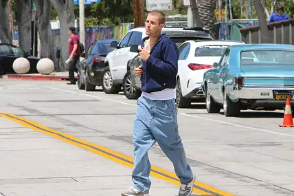 Justin Bieber rennt über eine Straße. Er trägt Baggy Jeans und einen Hoodie.