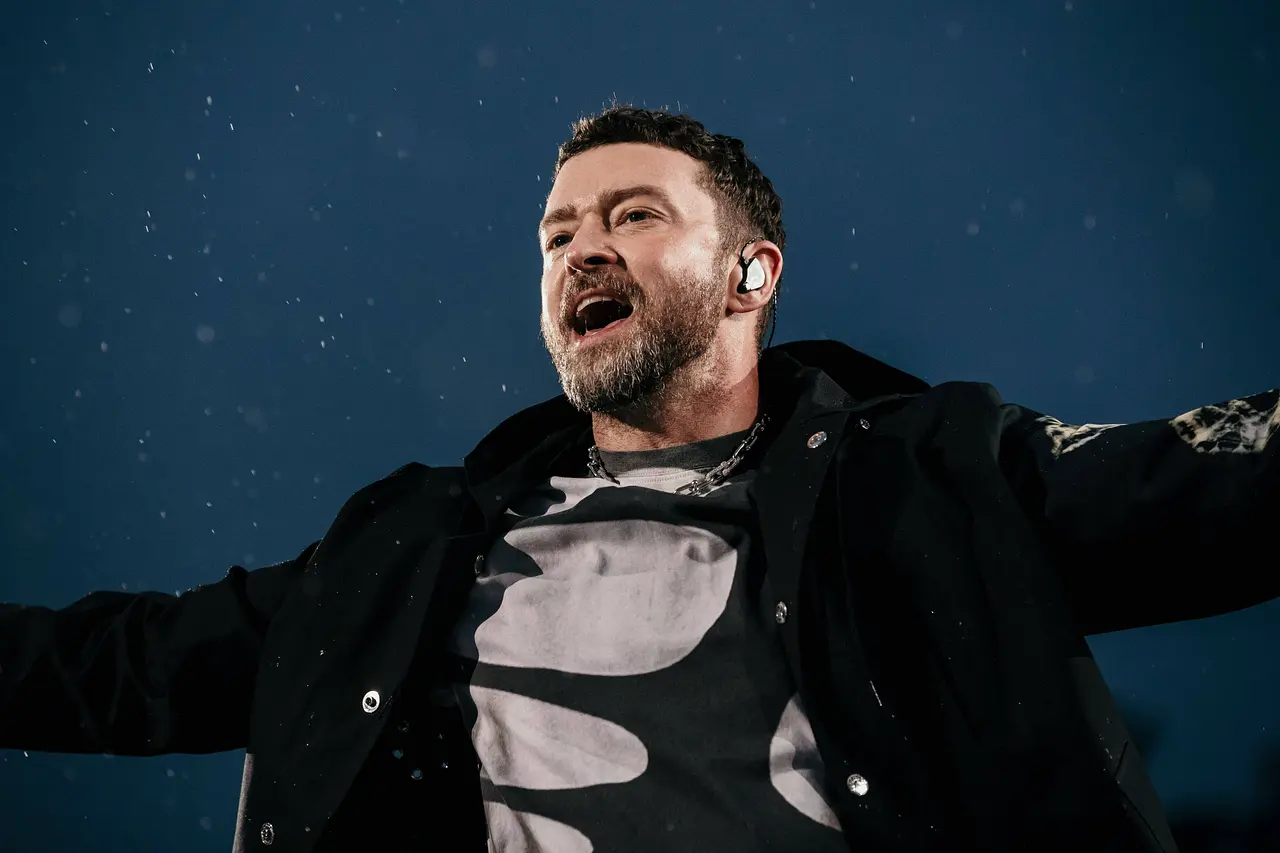 justin-timberlake-krankheit-imago821999947 Düsteres Foto. Justin Timberlake trägt eine schwarze Jacke und singt im Regen. - Foto: IMAGO / Scanpix