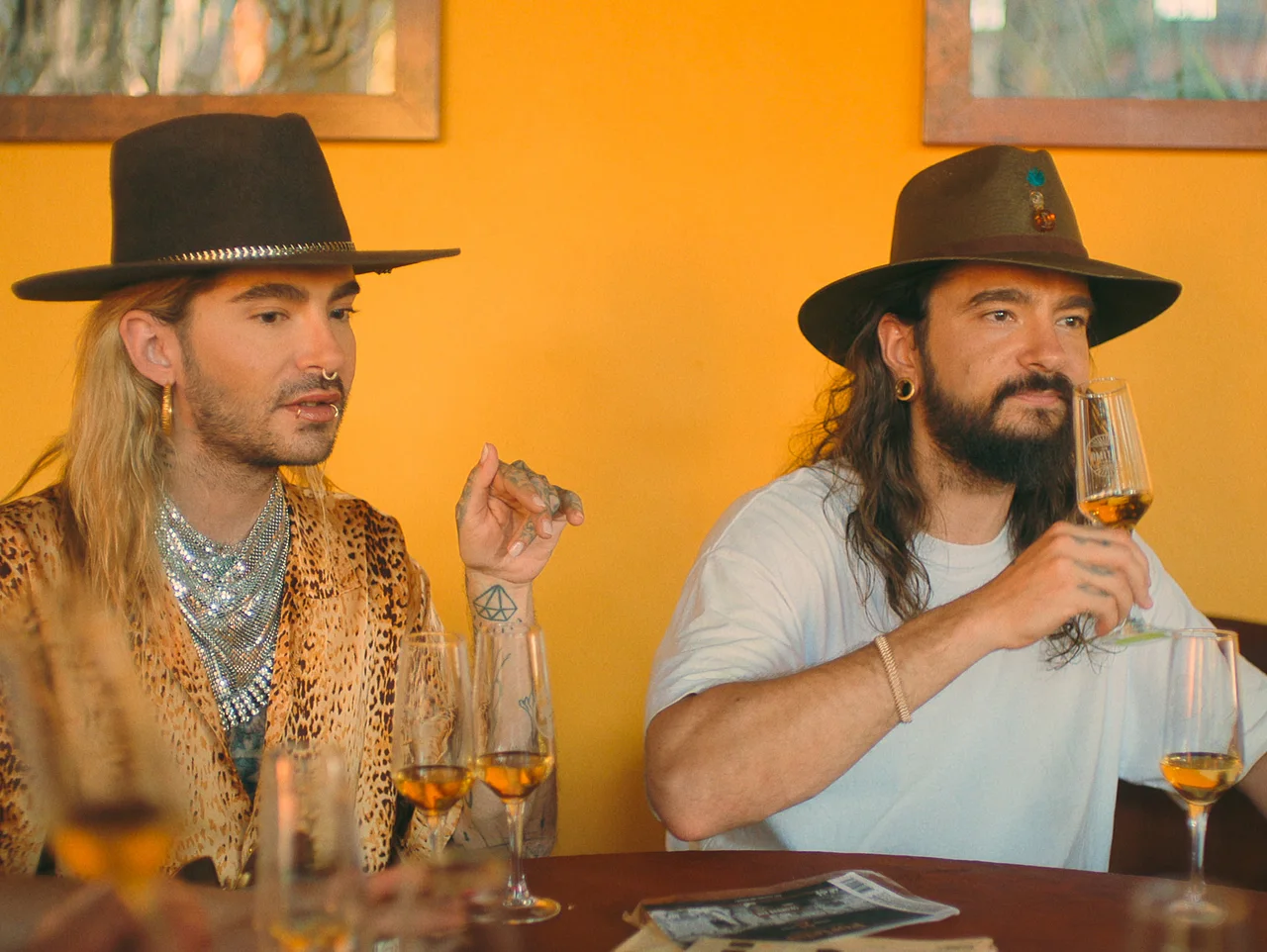 K&K_S2_E5_00_19_49_13 Bill Kaulitz und Tom Kaulitz sitzen mit Cowboyhüten an einem Tisch und trinken Alkohol. - Foto: Netflix