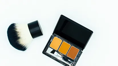 Mit einem Kabuki-Pinsel Make-up auftragen.