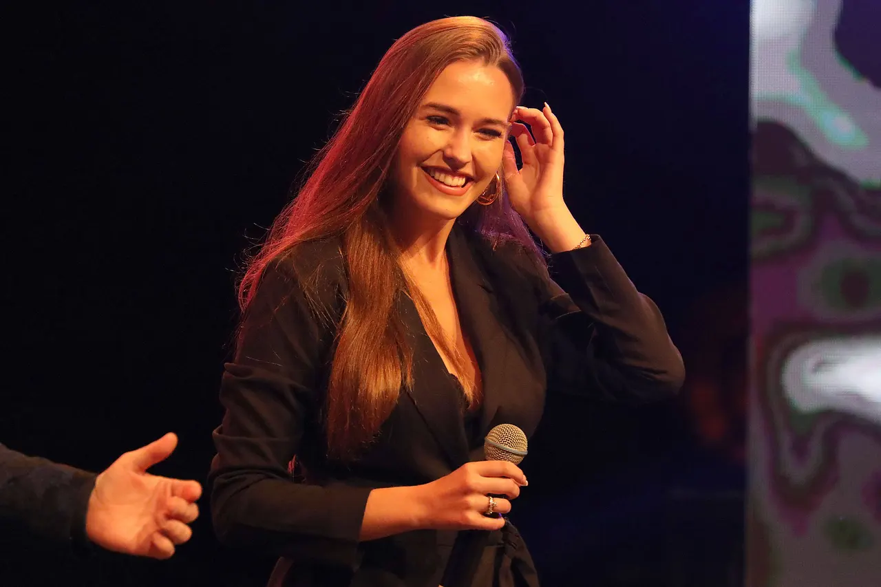 Laura Müller lacht herzlich und hält ein Mikrofon in der Hand. - Foto: IMAGO / Revierfoto