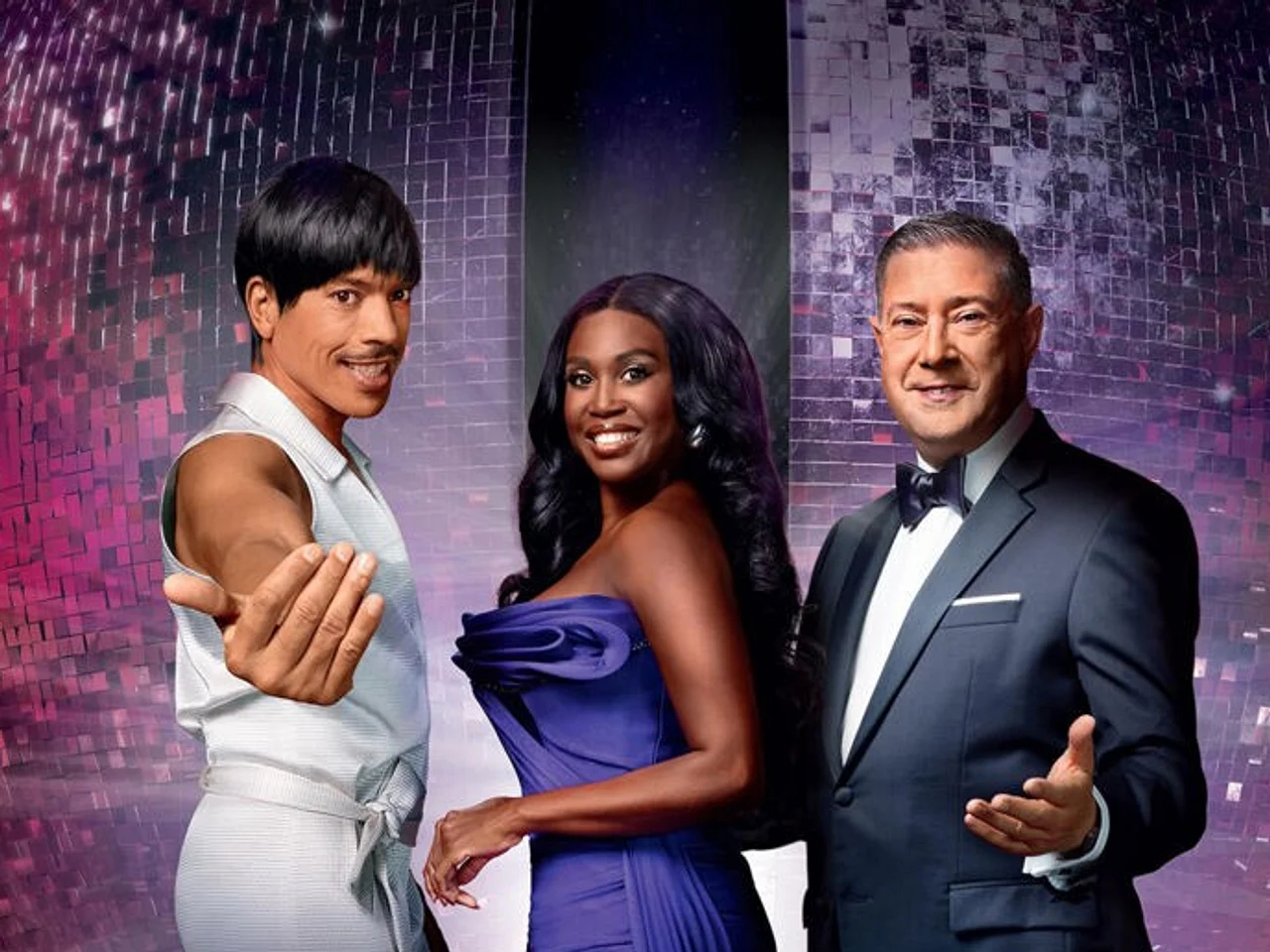 Profiturniertänzer Joachim Llambi, Profitänzerin Motsi Mabuse und Choreograf und Mode-Experte Jorge González vor einer Discokugel. Alle lächeln.