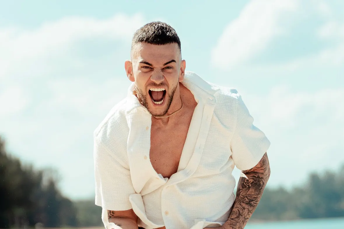 Serkan Yavuz posiert in einer triumphierenden Pose am Strand