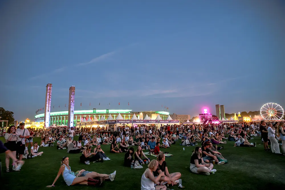 Bild von Festivalbesuchern des Lollapaloozas in Berlin, wie sie auf einer Wiese sitzen Bild von Festivalbesuchern des Lollapaloozas in Berlin, wie sie auf einer Wiese sitzen