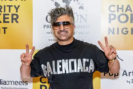 Lotto Chico posiert mit Sonnenbrille auf dem roten Teppich und zeigt das Peace-Zeichen.