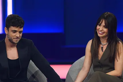 Luca Hänni und Christina Hänni halten auf der Bühne Händchen. Während er betroffen nach unten schaut, lacht sie. 