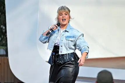 Maite Kelly steht in Jeansjacke und Lederrock auf der Bühne und singt.
