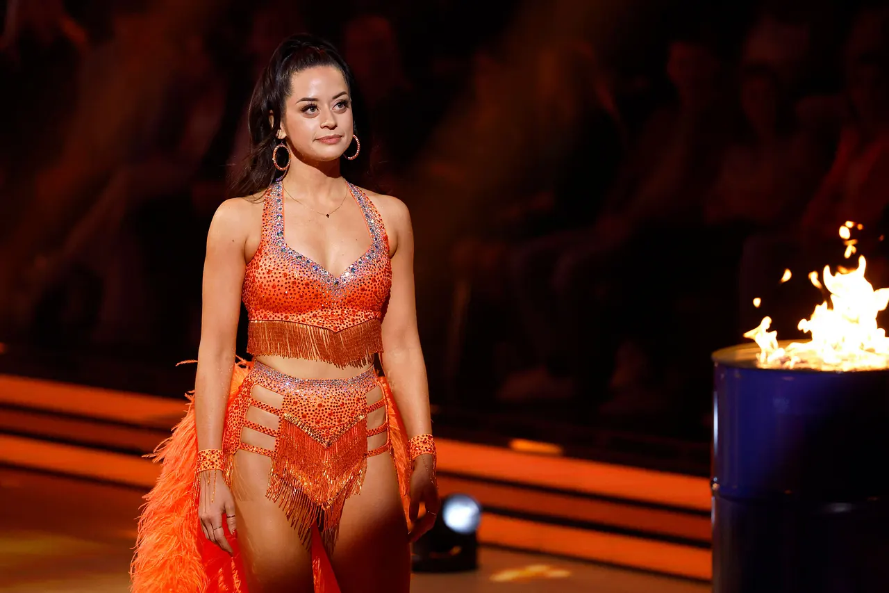 Malika Dzumaev steht bei "Let's Dance" auf dem Parkett, sie trägt ein orangenes Kostüm und schaut ernst.