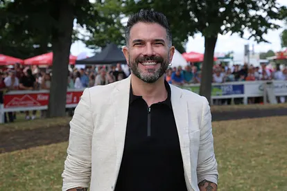 Marc Terenzi steht auf einer Wiese und grinst in die Kamera.
