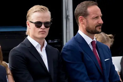 Marius Borg Høiby sitz neben Prinz Hakon, beide schauen ernst.