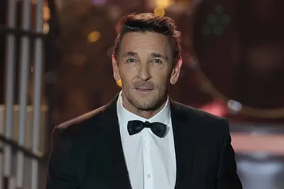 Mark Keller steht im Smoking auf der Bühne.
