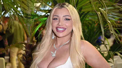 Melody Haase lächelt in die Kamera, um den hals trägt sie eine silberne Halskette mit dem Playboy-Hasen als Anhänger. Sie trägt zudem Playboy-Ohrringe.