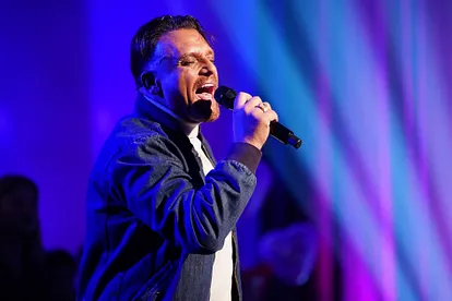 Nach Menowin Fröhlichs DSDS-Sieg: Jetzt überschlagen sich die Vorwürfe Menowin performt mit geschlossenen Augen und Mikrofon in der Hand auf einer Bühne mit blau-violetter Beleuchtung.