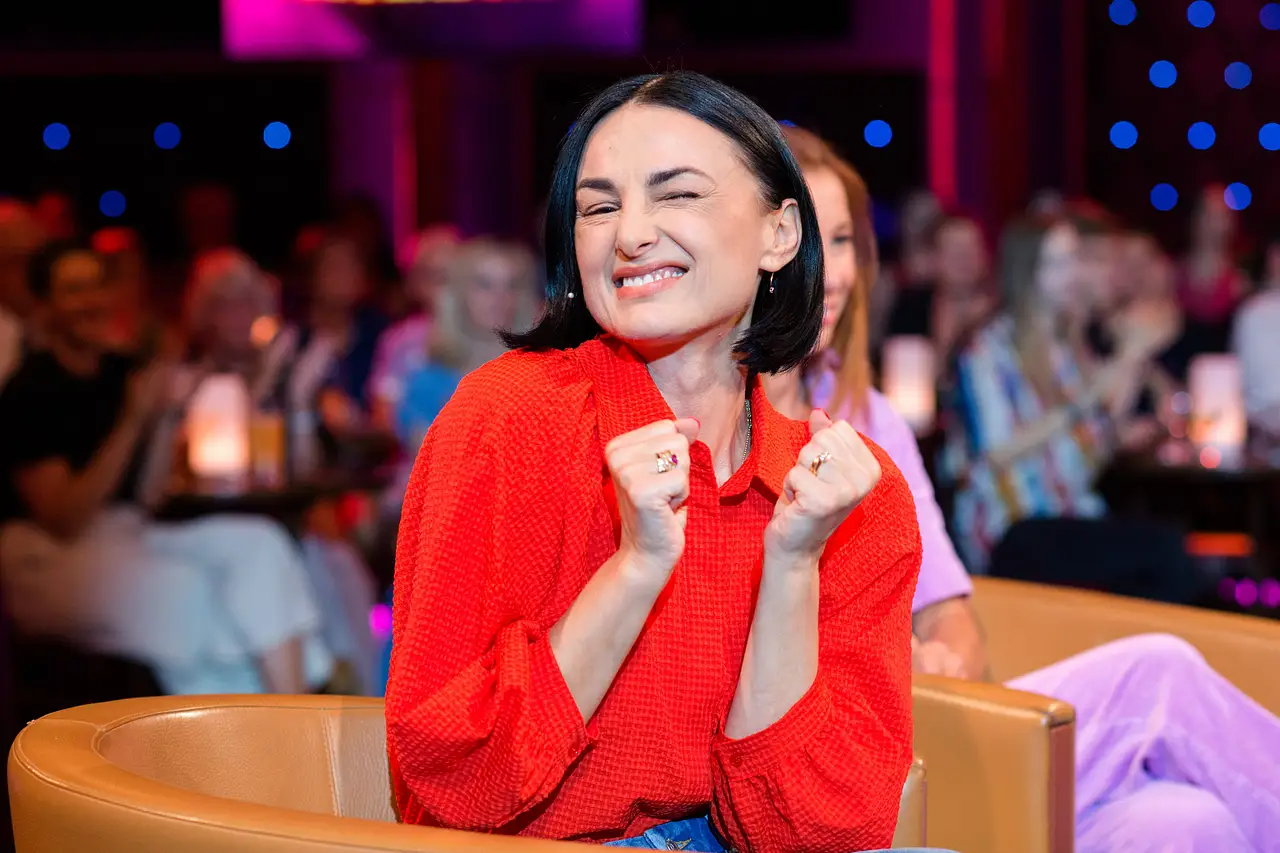 Mimi Fiedler trägt eine rote Bluse und hält grinsend ihre Arme vor die Brust.  - Foto: IMAGO / STAR-MEDIA
