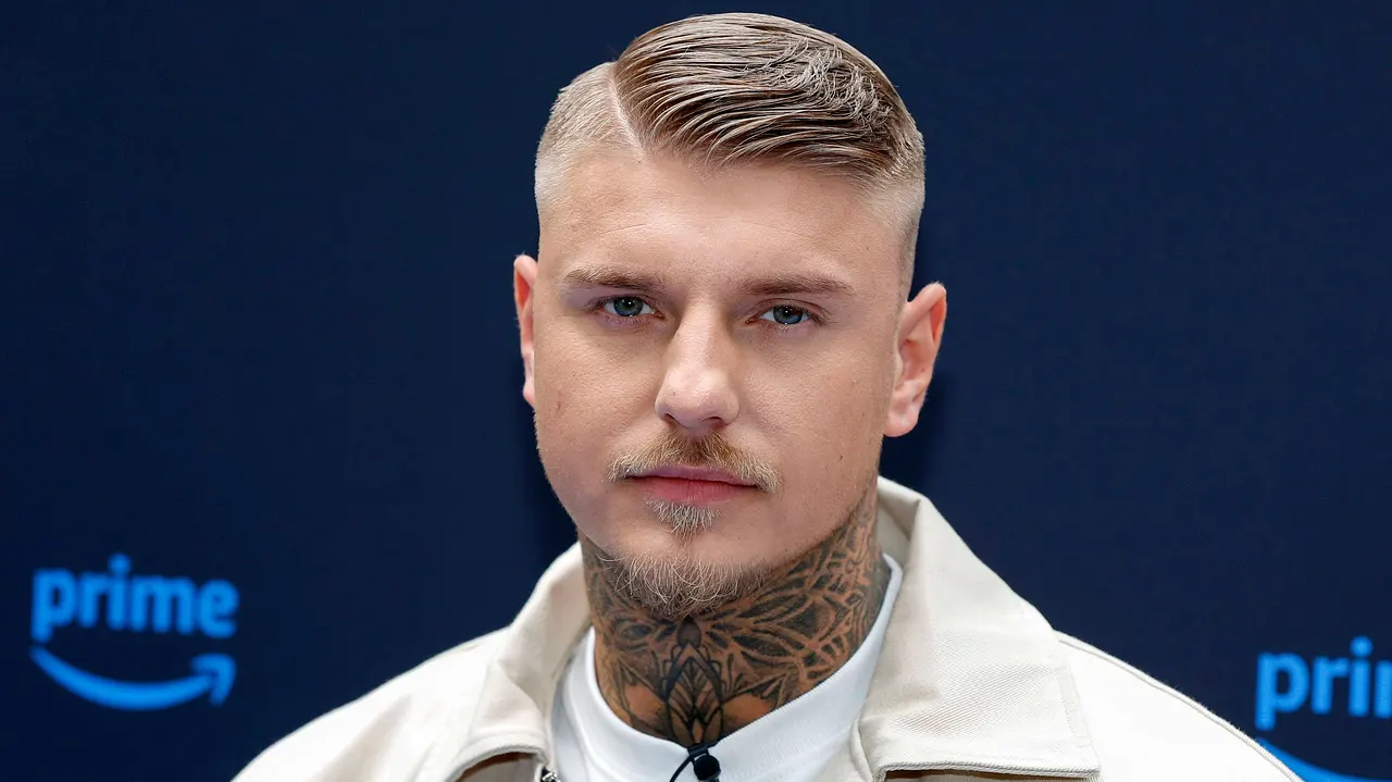 Paco Herb weiß, wie er seine Reality-Kollegen bei "The 50" lenken muss Paco Herb in weißem T-Shirt mit beiger Jacke auf dem Teppich von der Premiere von The 50, er hat einen durchdringenden ernsten Blick - Foto: IMAGO / Future Image