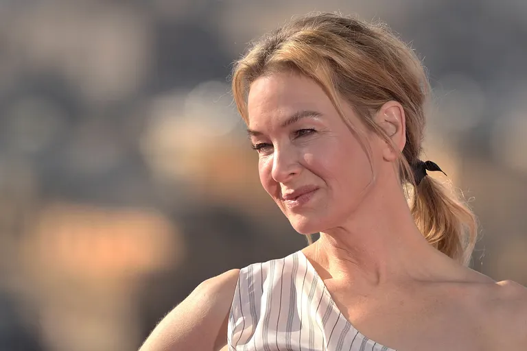 Renée Zellweger trägt ein einen Zopf und wird lächelnd von der Seite abgelichtet. 