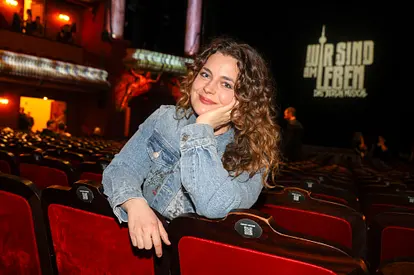 Ronja Forcher: Traurige Erinnerung! Ronja Forcher im Theater, sie stützt sich an einer Sessellehne und blickt lächelnd in die Kamera.