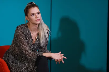 Sara Kulka sitzt mit ernstem Gesichtsausdruck auf einem Stuhl und hat die Hände gefaltet.