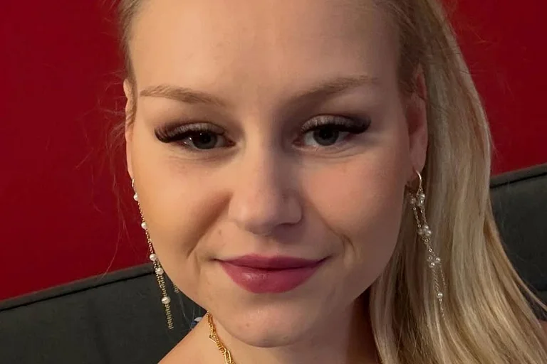 Sarah Jane Wollny schaut in die Kamera und lächelt leicht.
