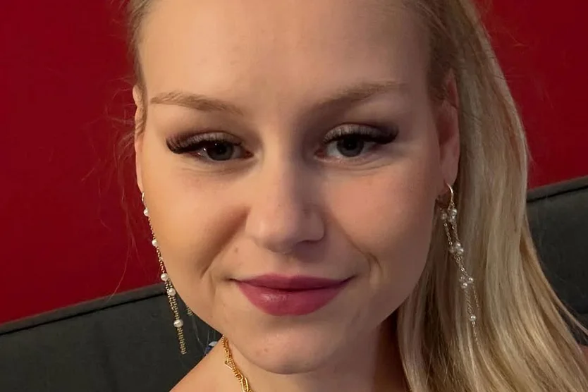 Sarah Jane Wollny schaut in die Kamera und lächelt leicht.