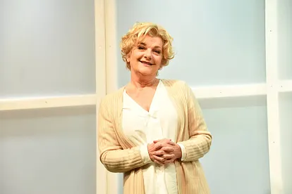 Saskia Vester hat die Hände vor dem Bauch und lächelt leicht.